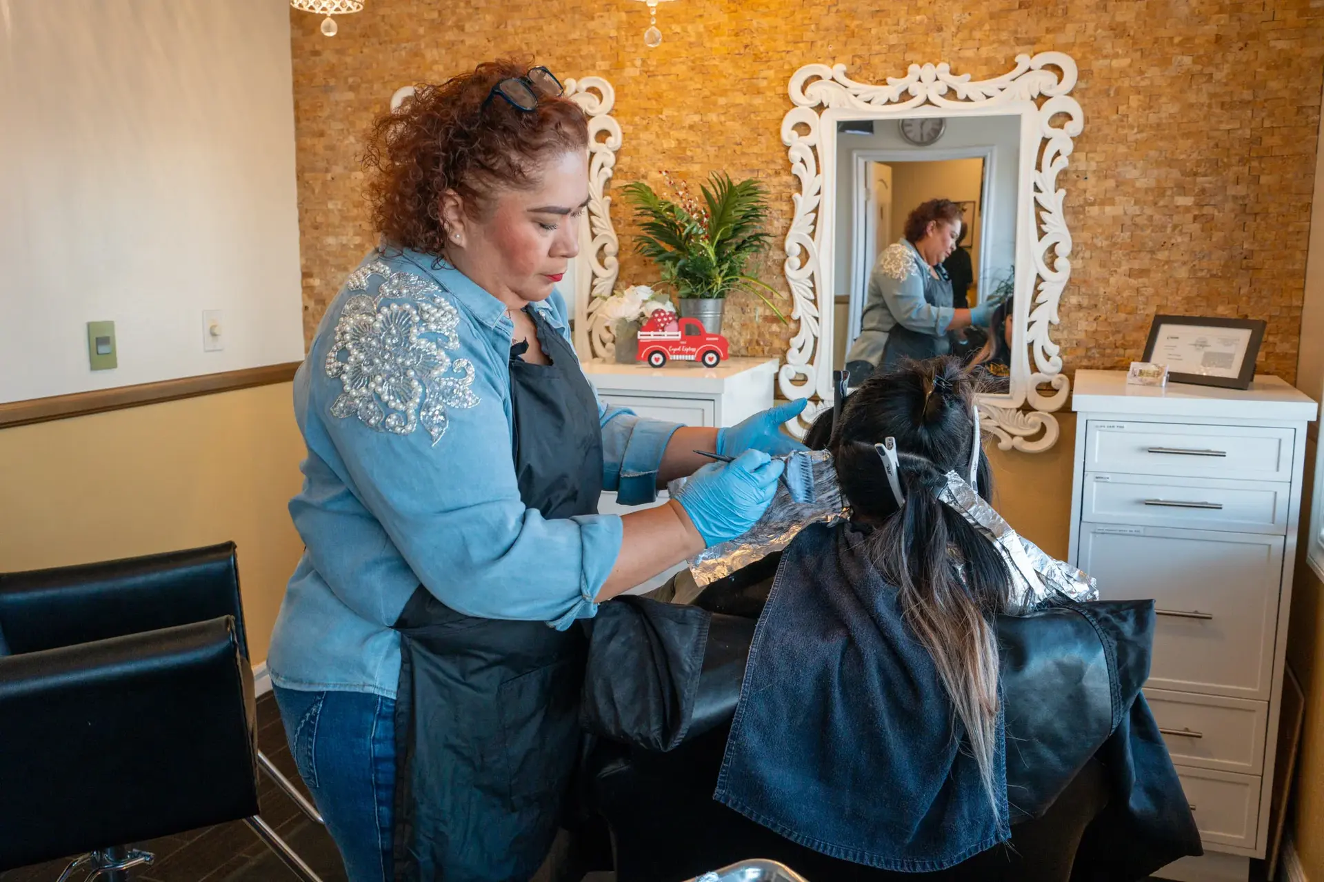 Salon owner bleaching client hair at styling station at F&J Beauty Studio in Anaheim, CA